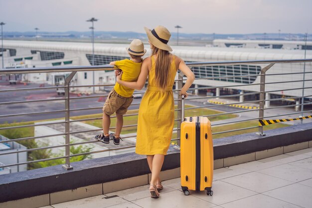 Family at airport before flight Mother and son waiting to board at departure gate of modern international terminal Traveling and flying with children Mom with kid boarding airplane yellow family look