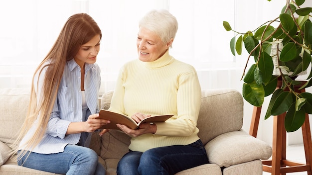 Family album. Senior mother and daughter looking photos, spending time together at home