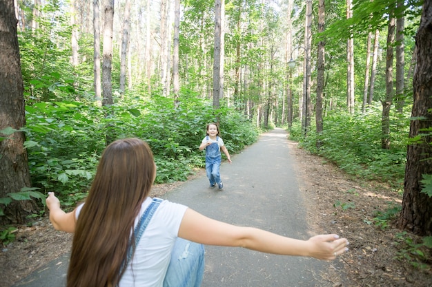 写真 家族と自然の概念-魅力的な若い女性は公園で彼女の小さな娘と楽しんでいます。