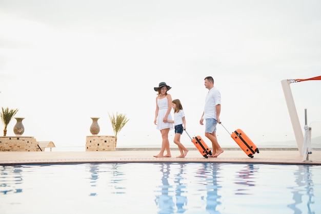 Famiglia che arriva in un hotel di lusso con le valigie a bordo piscina