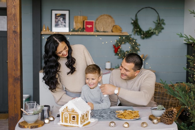 The family bakes a gingerbread house for Christmas with sweets the father puts icing