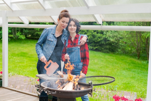 Family barbecue mom and daughter grilling with in a country house outdoors