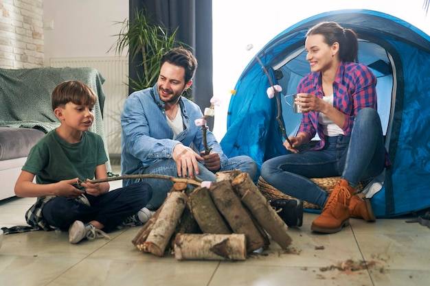 Photo family barbecuing marshmallow and camping at home