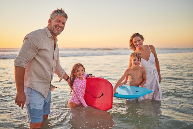 Spiaggia per famiglie e body board bambini con i genitori in acqua durante le vacanze estive mamma papà e bambini che fanno surf nell'oceano al tramonto in australia libertà divertimento e vacanza uomo e donna felici giocano tra le onde