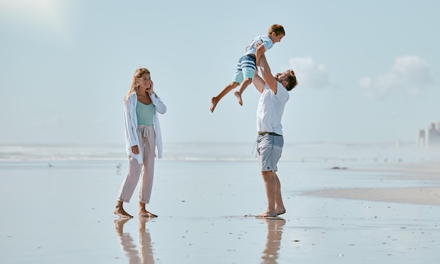 Family beach and father lifting kid on vacation holiday or summer trip outdoors Love support and care of mother man and boy playing bonding and having fun while enjoying quality time together