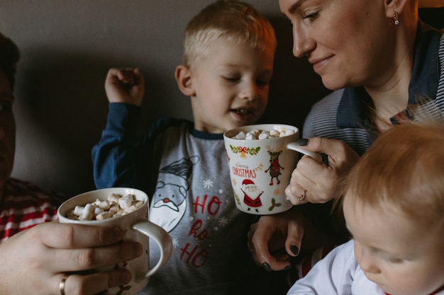 Семья перед рождеством дома пьет горячий шоколад с зефиром