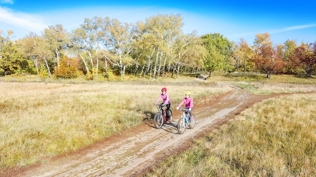 Family on bikes autumn cycling outdoors, active mother and kid on bicycles