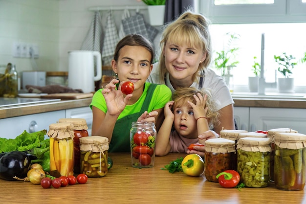 Photo family canning vegetables in jars in the kitchen selective focus