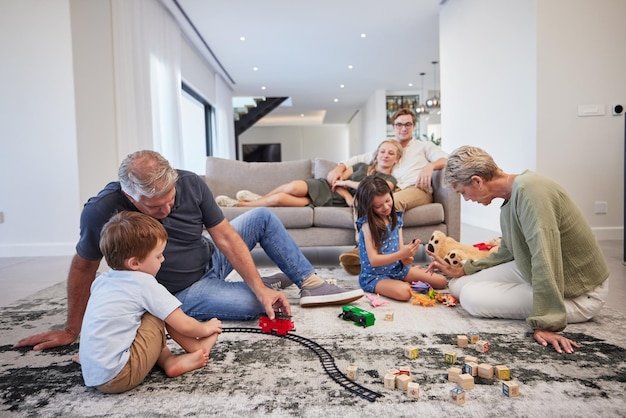 Foto cura della famiglia i bambini amano e i nonni felici con i giocattoli in soggiorno con i bambini sorridono il gioco del treno e l'orsacchiotto in casa madre e padre si rilassano sul divano con gli anziani e i giochi dei fratelli