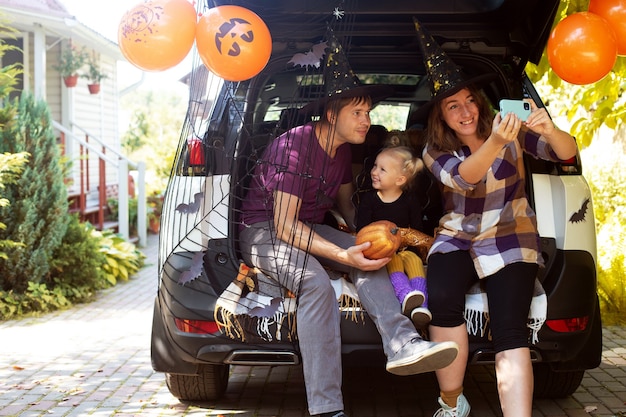 Famiglia che celebra il bagagliaio di un'auto di halloween divertendosi insieme autunno