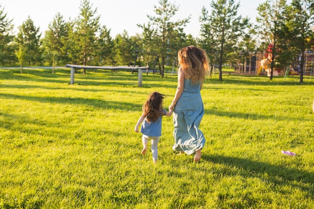 Family and child concept  mother and daughter walking in the park and enjoying the beautiful nature