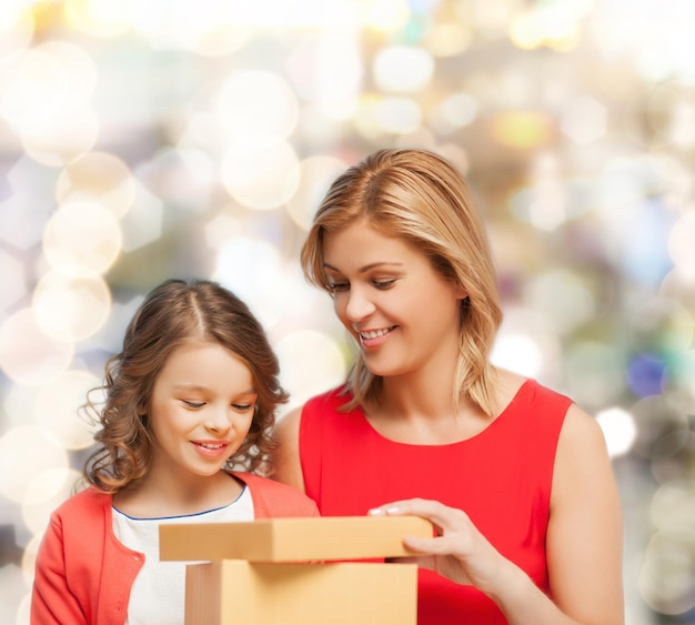 family, child, holiday and party concept - smiling mother and daughter with gift box