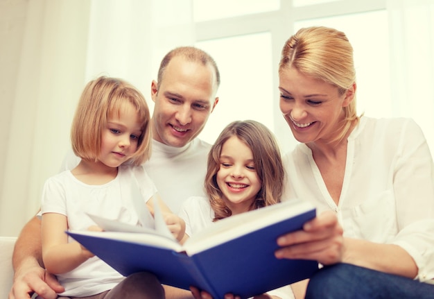 family, child and home concept - smiling family and two little girls with book at home