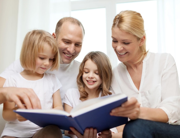 family, child and home concept - smiling family and two little girls with book at home