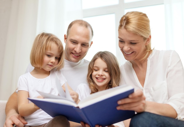 family, child and home concept - smiling family and two little girls with book at home