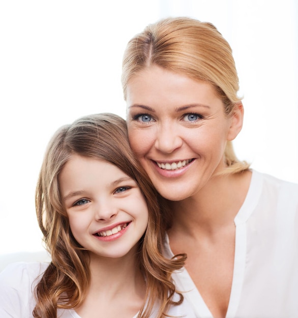 family, child and home concept - smiling mother and little girl at home