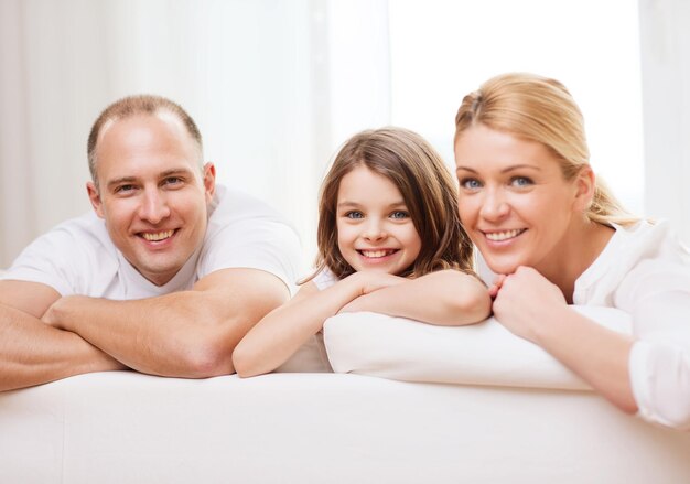 family, child and home concept - smiling parents and little girl at home