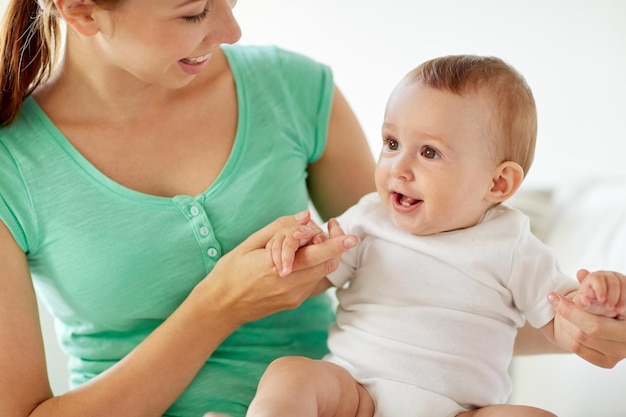 family, child and parenthood concept - close up of happy smiling young mother with little baby at home