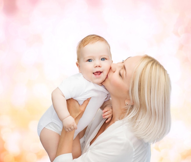 가족, 어린이 및 부모 개념 - 웃는 아기에게 키스하는 행복한 어머니
