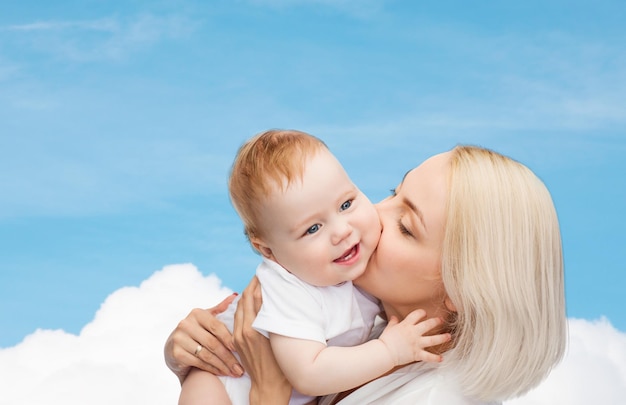 family, child and parenthood concept - happy mother kissing smiling baby