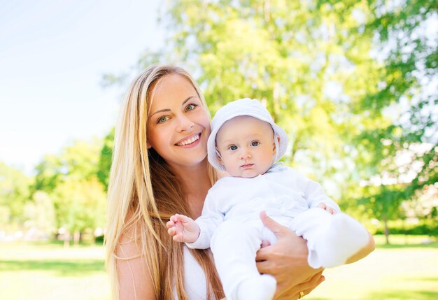 family, child and parenthood concept - happy mother with little baby in park