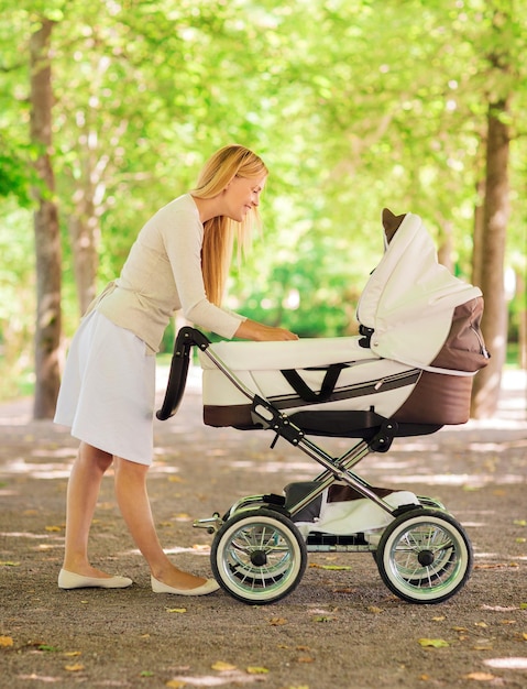 Foto concetto di famiglia, bambino e genitorialità - madre felice con passeggino nel parco