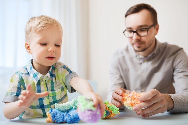 家族、子供時代、創造性、活動、人のコンセプト – 幸せな父と幼い息子が家でボール粘土で遊ぶ