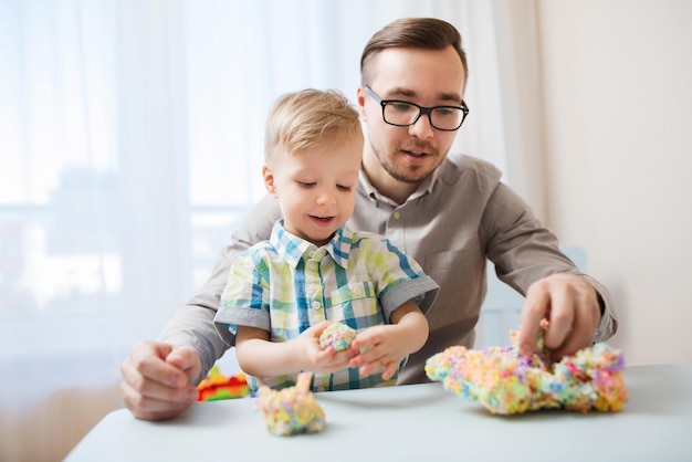 семья, детство, творчество, деятельность и концепция людей - счастливый отец и маленький сын играют с шаровой глиной дома