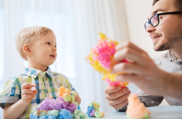 家族、子供時代、創造性、活動、人のコンセプト – 幸せな父と幼い息子が家でボール粘土で遊ぶ