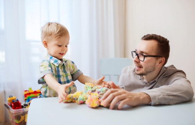 家族、子供時代、創造性、活動、人のコンセプト – 幸せな父と幼い息子が家でボール粘土で遊ぶ
