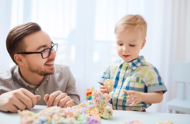 家族、子供時代、創造性、活動、人のコンセプト – 幸せな父と幼い息子が家でボール粘土で遊ぶ