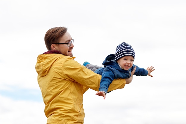 family, childhood, fatherhood, leisure and people concept - happy father and little son playing and having fun outdoors