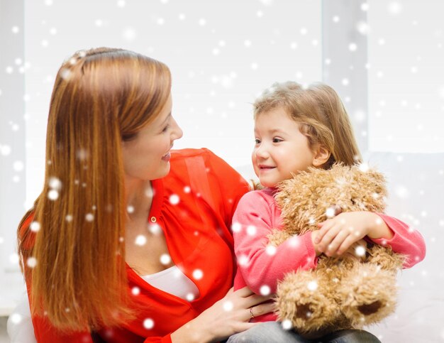 концепция семьи, детства, праздников и людей - счастливая мать и дочь с игрушкой плюшевого мишки