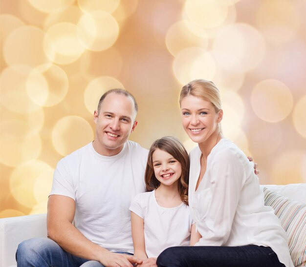 family, childhood, holidays and people - smiling mother, father and little girl over beige lights background