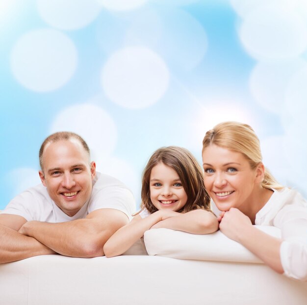 family, childhood, holidays and people - smiling mother, father and little girl over blue lights background