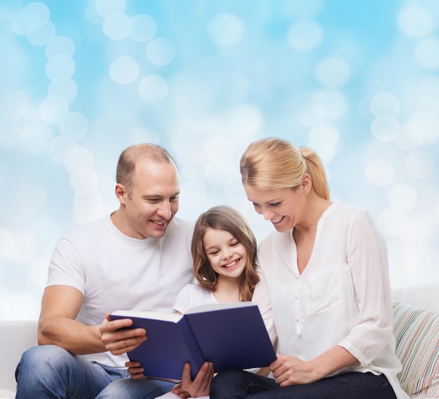 family, childhood, holidays and people - smiling mother, father and little girl reading book over blue lights background