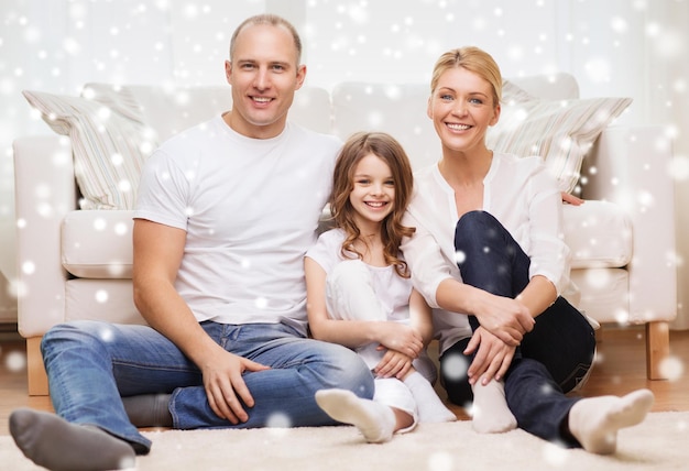 семья, детство, люди и концепция дома - улыбающиеся родители с маленькой девочкой, сидящей дома на полу