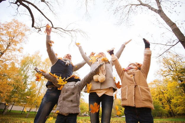 写真 家族、子供時代、季節と人々の概念-公園で紅葉で遊ぶ幸せな家族