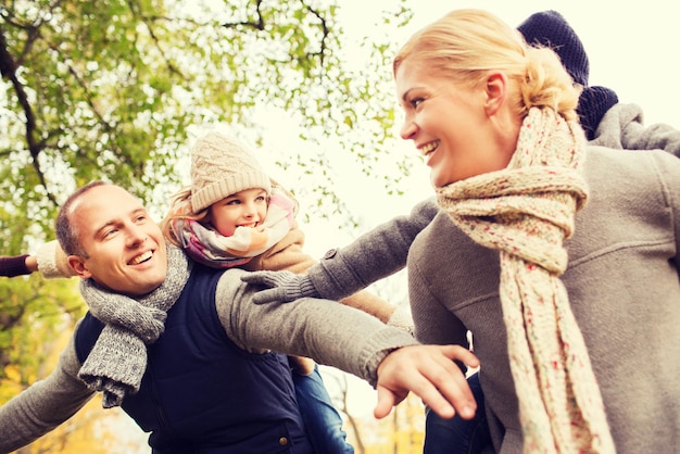 Concetto di famiglia, infanzia, stagione e persone - famiglia felice che si diverte nel parco autunnale