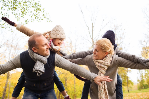 family, childhood, season and people concept - happy family having fun in autumn park