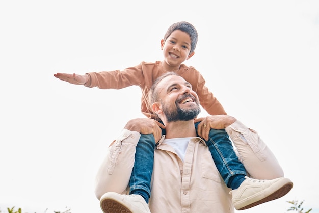 Photo family children and boy sitting on the shoulders of his father outdoor while bonding from below fun kids and love with a man carrying his son outside while spending time together being playful