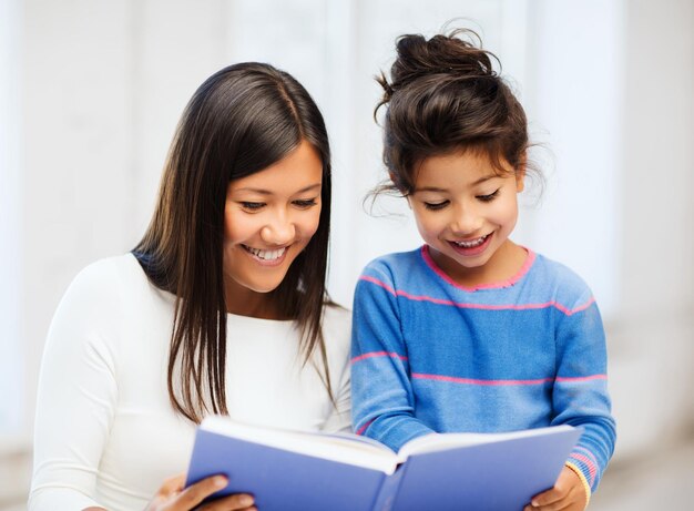 family, children, education, school and happy people concept - mother and daughter with book