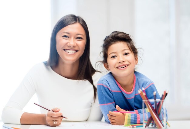 family, children and happy people concept - mother and daughter drawing