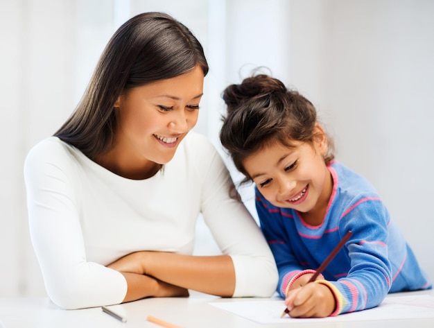 family, children and happy people concept - mother and daughter drawing