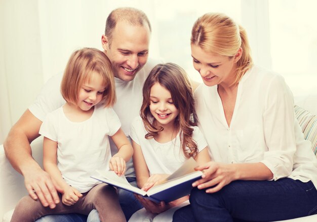 Foto concetto di famiglia, bambini e casa - famiglia sorridente e due bambine con il libro a casa