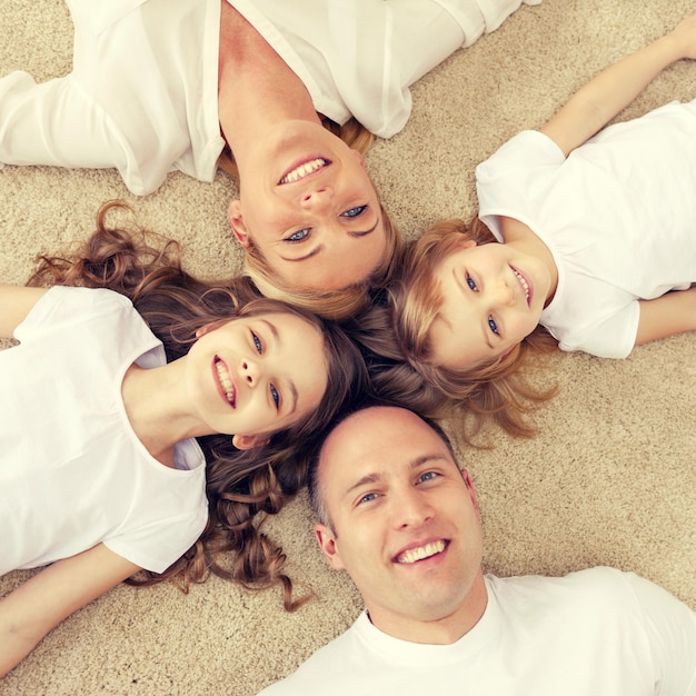 Photo family, children and home concept - smiling family with and two little girls lying in circle on floor at home