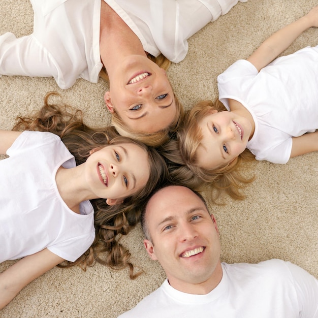 family, children and home concept - smiling family with and two little girls lying in circle on floor at home