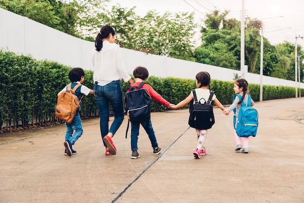 Family children kid son girl and boy kindergarten walking going to school holding hand with mother mom