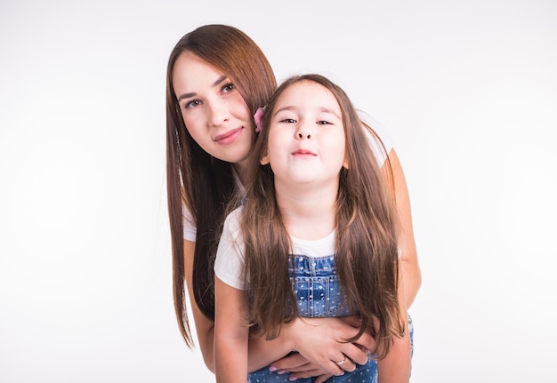 Family, children and parenthood concept - Young woman with her little cute child on white surface