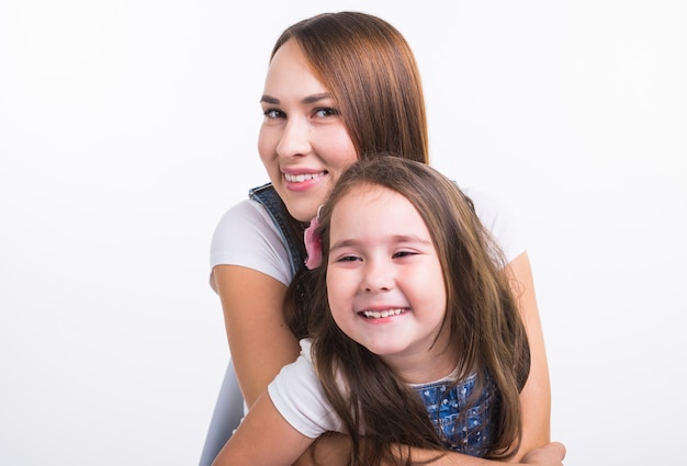 Family, children and parenthood concept - Young woman with her little cute child on white wall